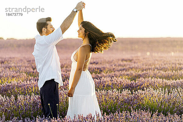 Glücklicher Mann tanzt mit Frau im Lavendelfeld