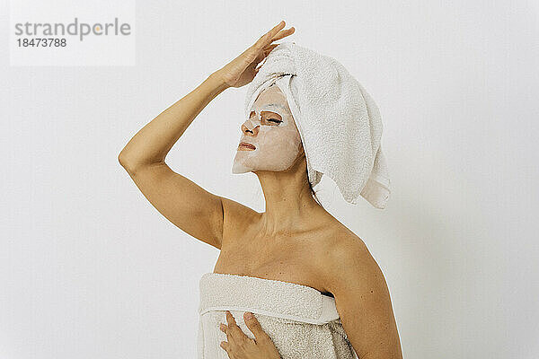 Frau mit Gesichtsmaske steht vor weißer Wand