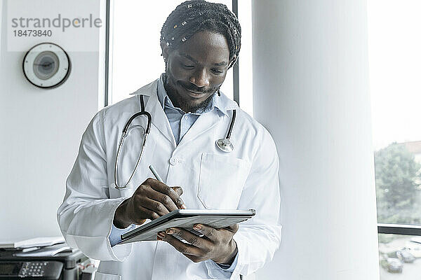 Junger Arzt nutzt Tablet-PC in der Klinik