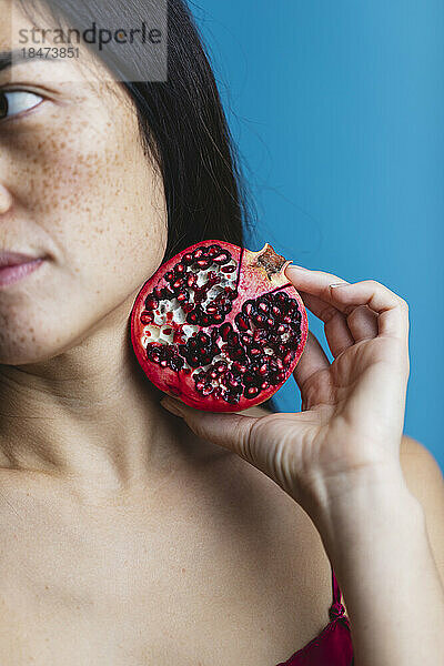 Woman holding pomegranate against blue background