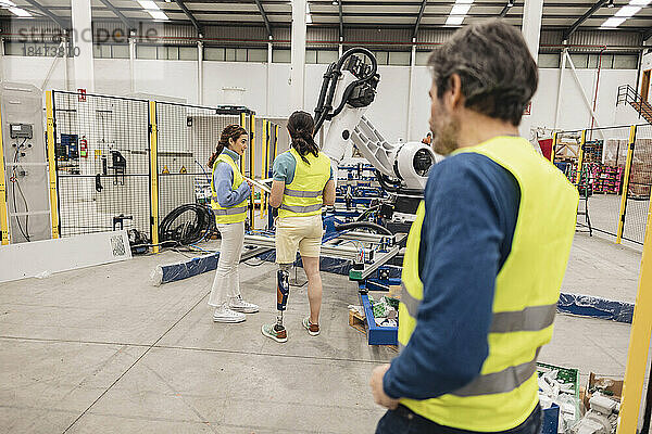Ingenieure tragen reflektierende Kleidung in einer Roboterfabrik