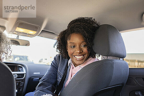 Glückliche junge Frau sitzt im Auto
