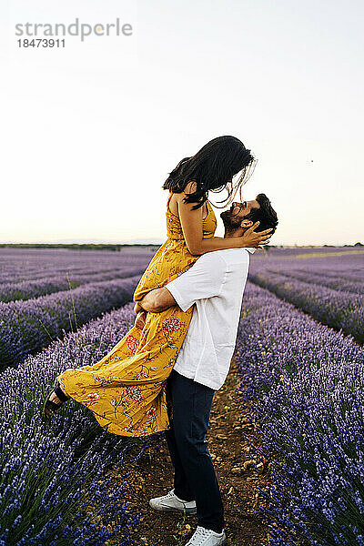 Man carrying woman in lavender field at sunset