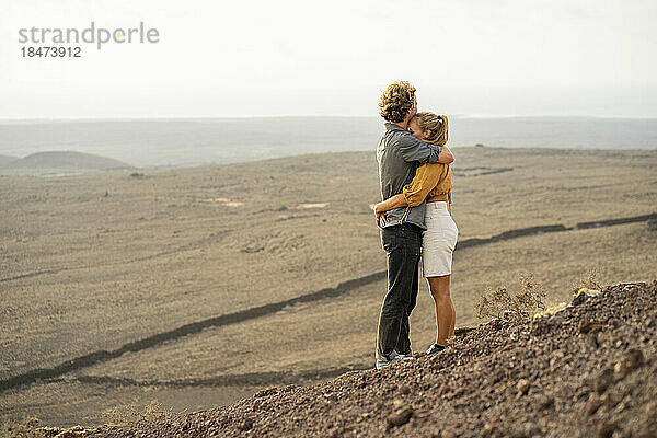 Romantisches junges Paar umarmt sich auf dem Berg