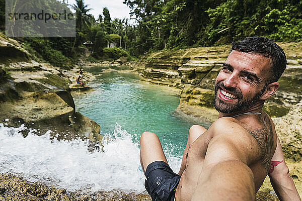 Glücklicher Mann  der ein Selfie am Wasserfall macht