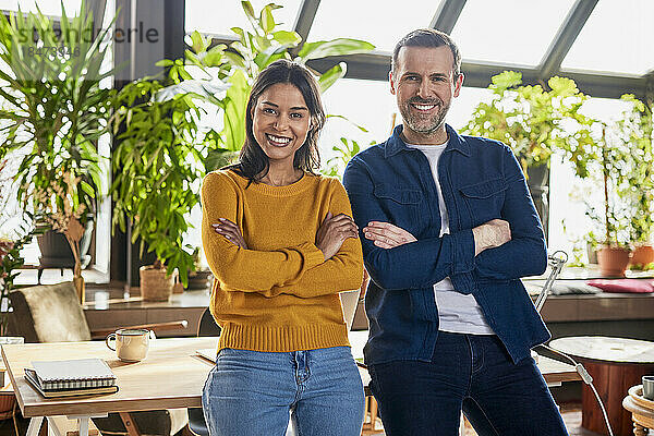 Smiling diverse business colleagues with arms crossed at loft office