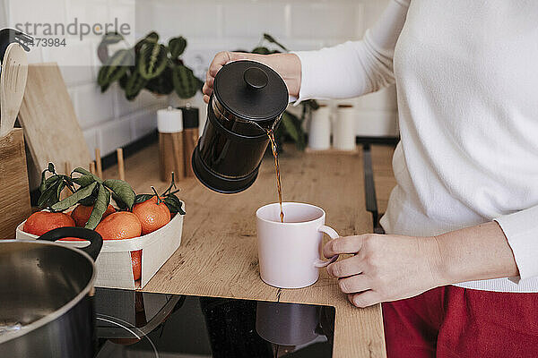 Frau gießt zu Hause Kaffee in eine Tasse