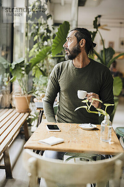 Reifer Mann mit Kaffeetasse sitzt im Café