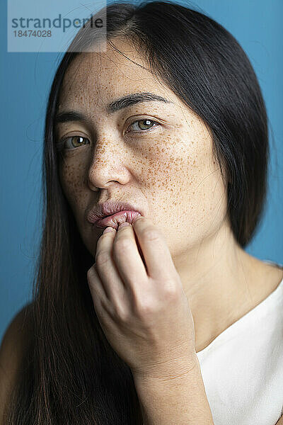 Woman with freckles in front of colored background