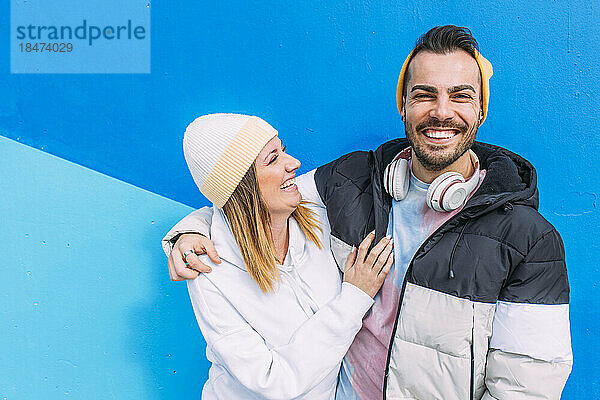 Glückliches junges Paar genießt es gemeinsam vor der blauen Wand