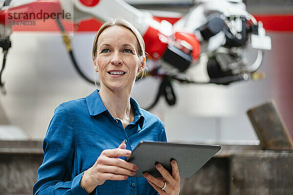 Nachdenklicher Ingenieur hält Tablet-PC in Roboterfabrik