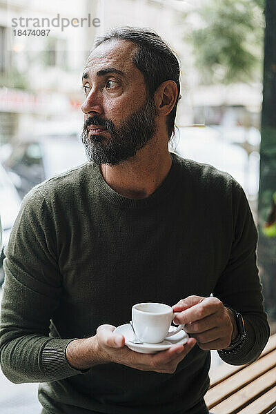 Nachdenklicher reifer Mann hält Kaffeetasse im Café