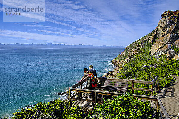 Südafrika  Ostkap  zwei Wanderer auf der Aussichtsplattform mit Blick auf Plettenberg Bay