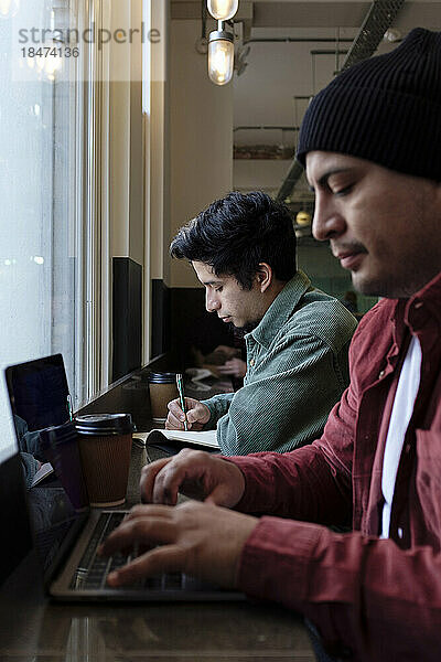Freiberufler arbeitet mit Bruder im Café am Laptop
