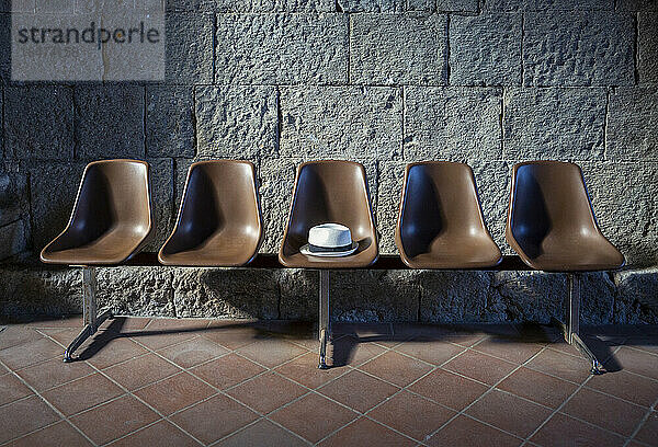 Hat on empty brown seat in front of stone wall