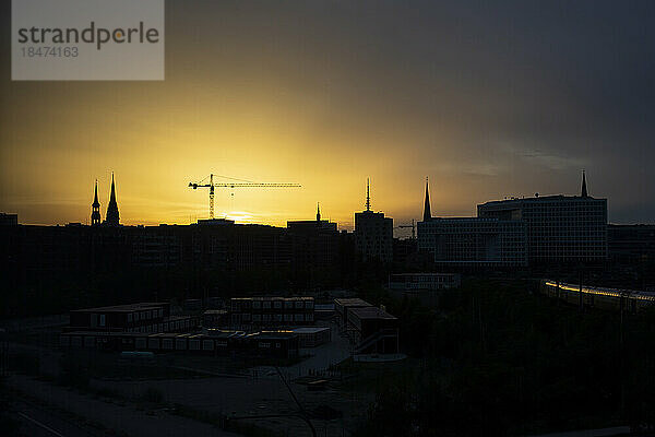 Deutschland  Hamburg  Silhouetten von Stadttürmen und Baukran bei Sonnenuntergang