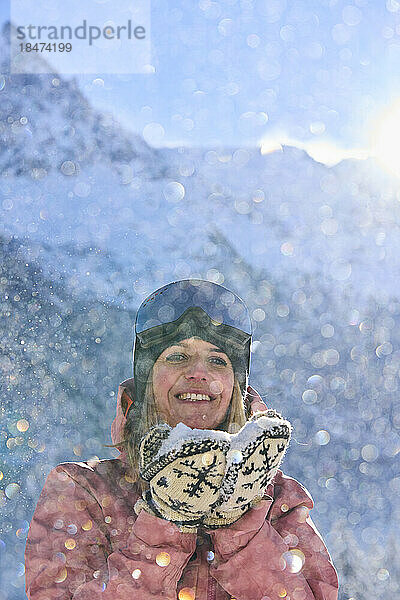 Glückliche Frau mit Schnee  die vor dem Berg steht