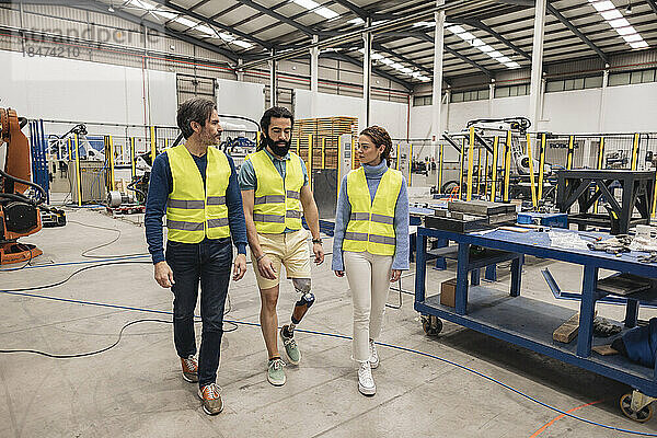 Ingenieure in reflektierender Kleidung gehen durch die Fabrik