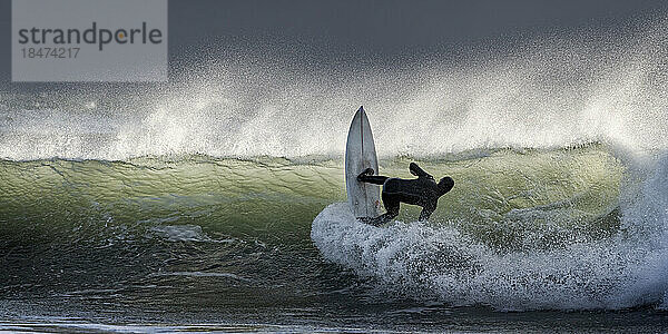 Mann surft im Urlaub auf Wellen im Meer