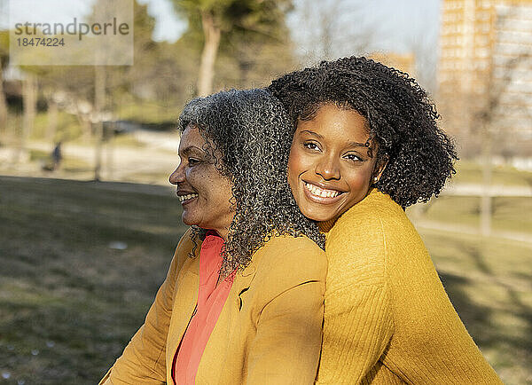 Glückliche junge Frau sitzt mit Mutter im Park