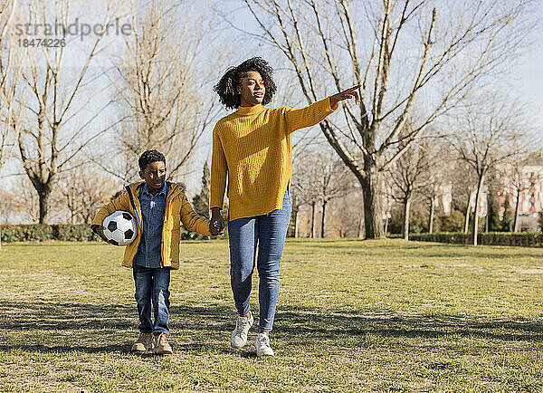 Woman walking with son pointing in park