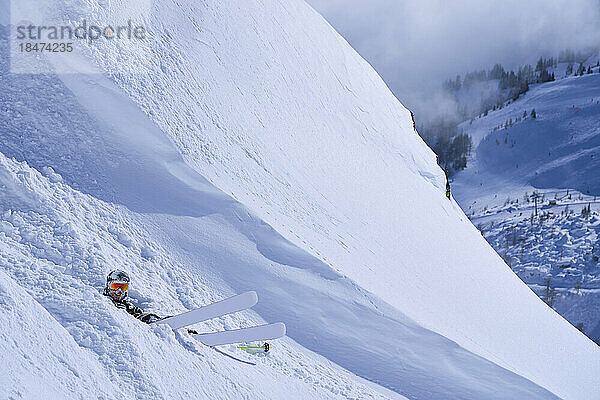 Reifer Mann mit Skiern entspannt auf Pulverschnee
