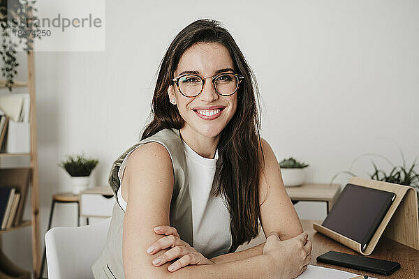 Glückliche Geschäftsfrau mit Brille am Schreibtisch im Büro