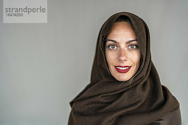 Glückliche Frau mit Hijab vor grauem Hintergrund