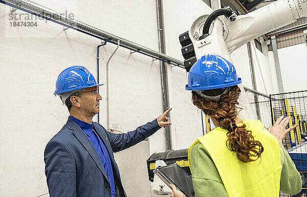 Ingenieure diskutieren über Roboterarm in Fabrik