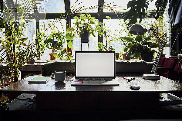 Laptop mit leerem Bildschirm auf dem Schreibtisch im Loftbüro