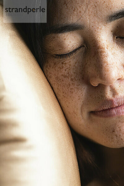 Woman with eyes closed resting on pillow