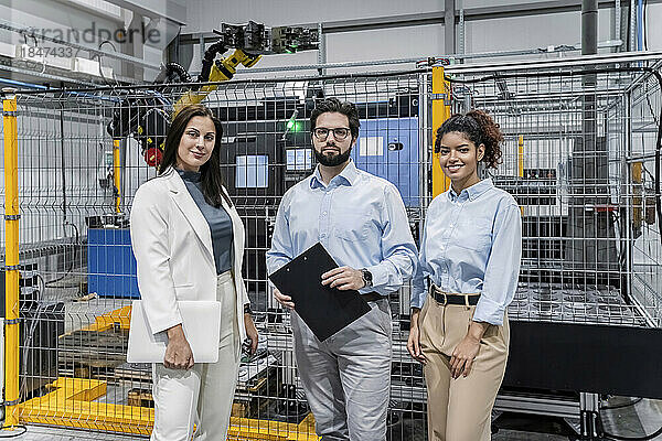 Lächelnde Geschäftsleute stehen in der Fabrik