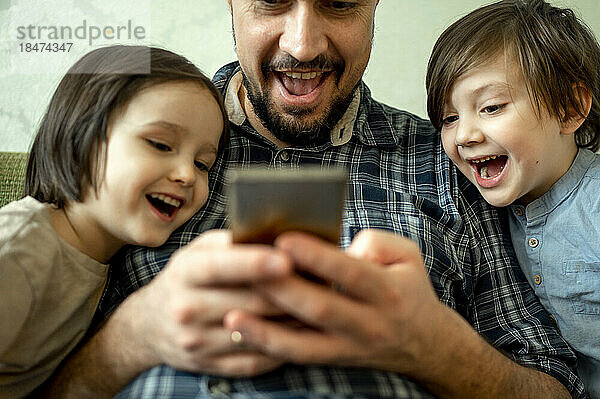 Glücklicher Vater teilt Smartphone mit Kindern zu Hause
