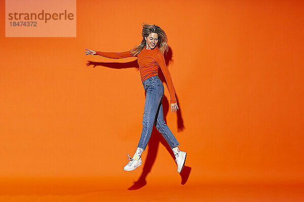 Lächelnde Frau schwebt vor orangefarbenem Hintergrund