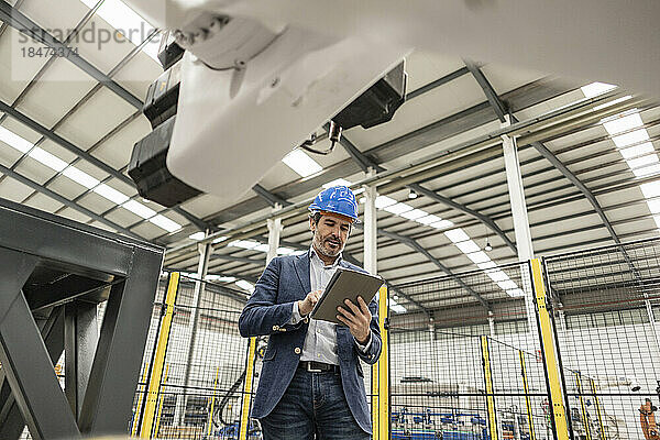 Ingenieur trägt Schutzhelm und nutzt Tablet-PC in der Fabrik