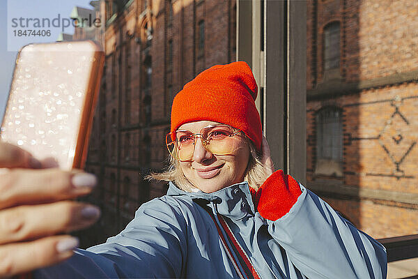 Frau in warmer Kleidung macht ein Selfie mit dem Smartphone