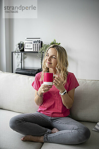 Nachdenkliche reife Frau sitzt mit einer Kaffeetasse zu Hause