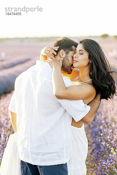 Mann umarmt junge Frau auf Lavendelfeld