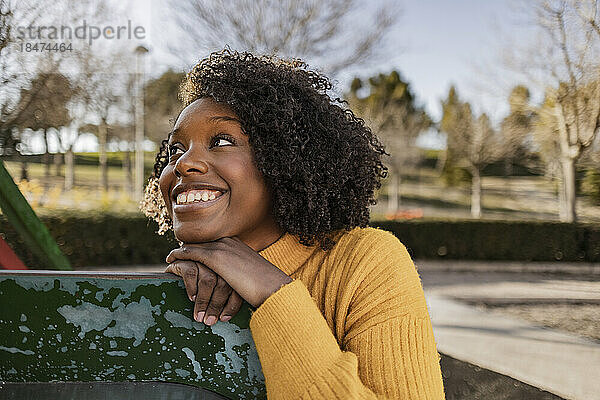 Nachdenklich lächelnde junge Frau lehnt auf Rutsche auf Spielplatz