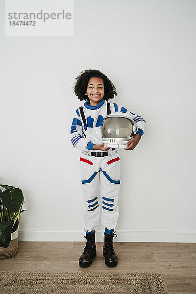 Elementary girl wearing space suit standing in front of white wall