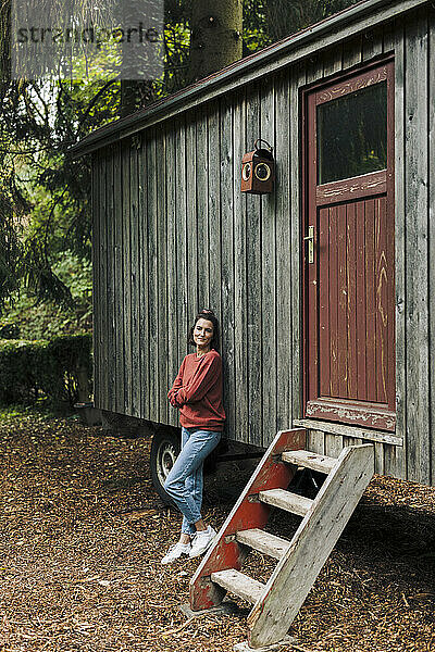 Lächelnde Frau stützte sich auf eine Holzhütte