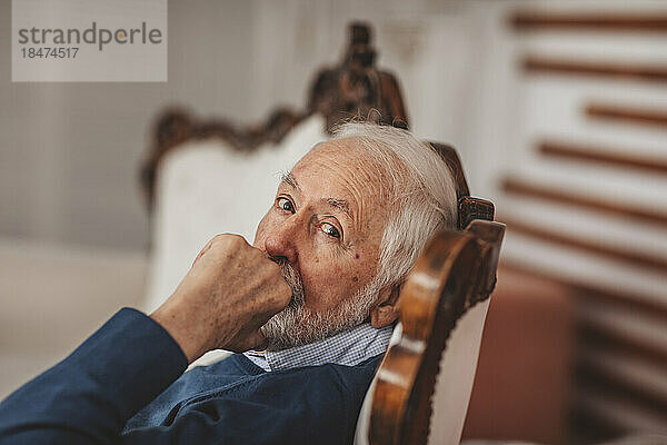Älterer Mann sitzt zu Hause auf einem Stuhl