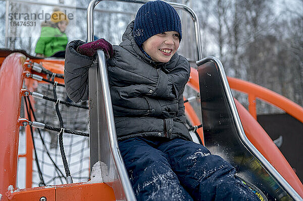 Junge spielt auf Rutsche im Spielplatz im Winterpark