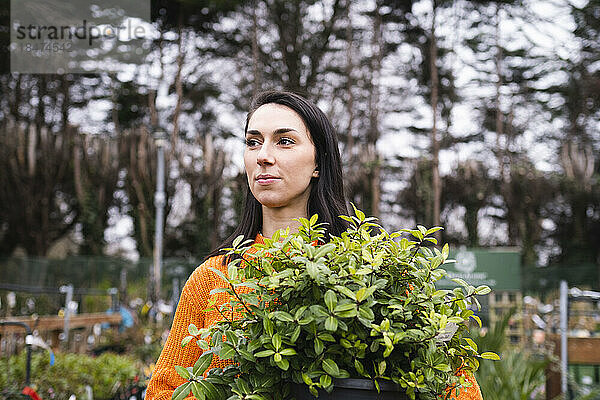 Junge Frau mit Topfpflanze im Gartencenter