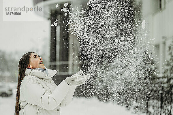 Glückliche Frau  die im Winter Schnee wirft