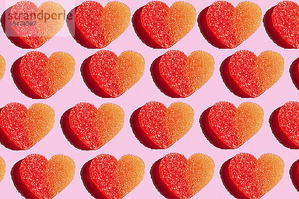 Pattern of heart shaped candy flat laid against pink background