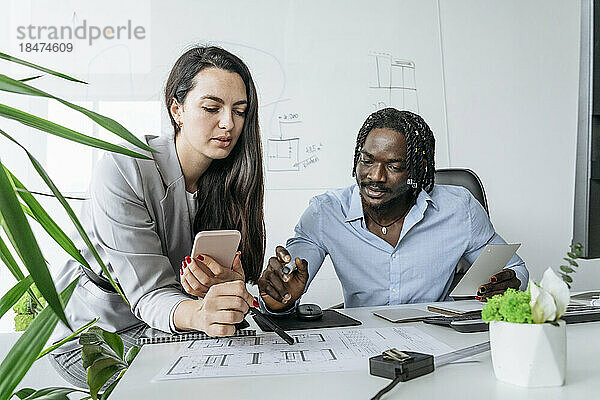 Architekt und Kollege diskutieren im Büro über den Bauplan