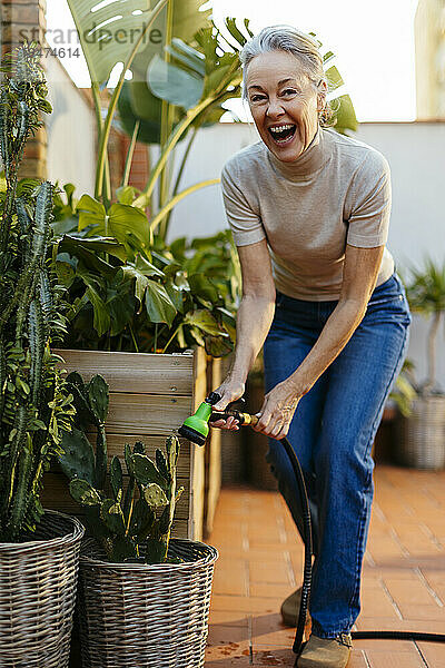 Cheerful mature woman watering plants