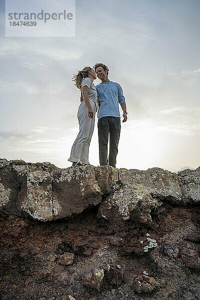 Lächelndes junges Paar steht am Rand einer Klippe