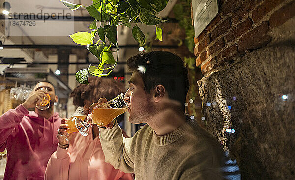 Junger Mann trinkt mit Freunden im Restaurant